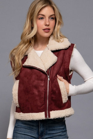 Woman wearing a burgundy and beige fleece vest against a gray background
