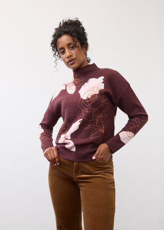 Woman wearing a floral sweater and pants.