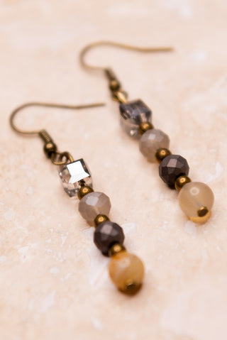 Beaded earrings with gold accents on a beige background