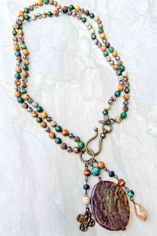 Multicolored beaded necklace with a large pendant on a textured white background