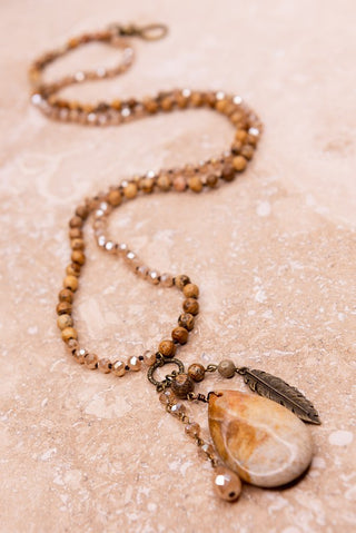Necklace with brown stone beads and charms including large stone, crystal bead and feather