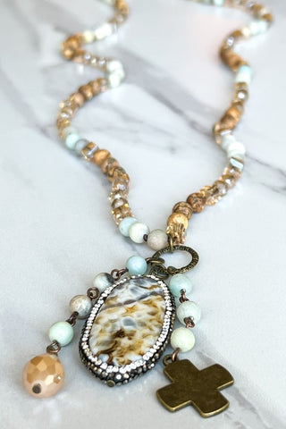 Necklace with beads and a cross pendant on a marble surface