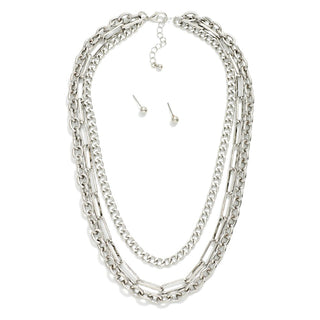 A three-layered silver chain necklace with matching stud earrings, displayed on a clean white background.