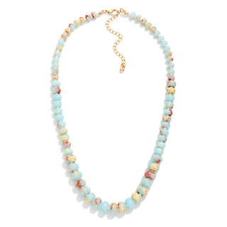 A beaded necklace featuring light blue, cream, and terracotta marbled beads, accented with small gold-toned spacer beads and a gold chain extender clasp, shown on a plain white background.