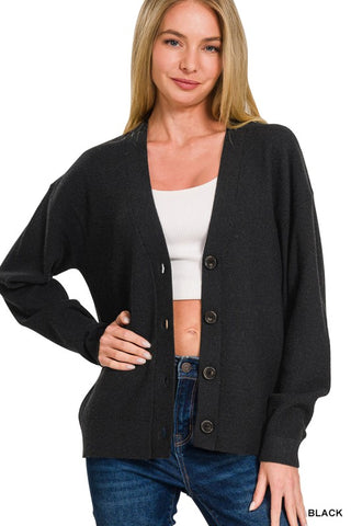 Woman wearing a black cardigan over a white top and blue jeans on a white background
