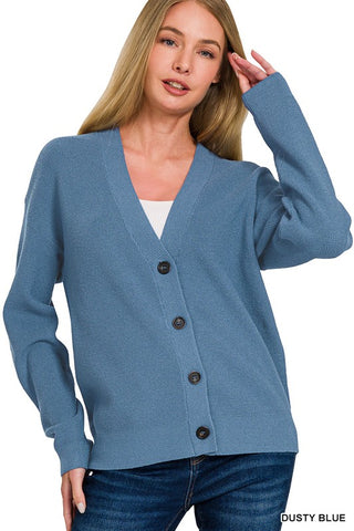 Woman wearing a dusty blue cardigan with black buttons on a white background