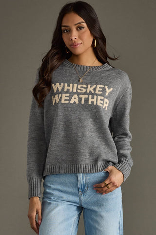 Woman wearing a gray sweater with 'Whiskey Weather' text against a gray background