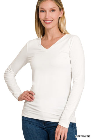 A woman modeling a long-sleeve V-neck top in off-white, paired with blue jeans, against a plain white background. A small text label in the bottom right corner reads 'OFF WHITE'.