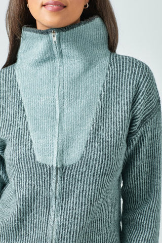 Close-up of a person wearing a textured green sweater with a zipper.