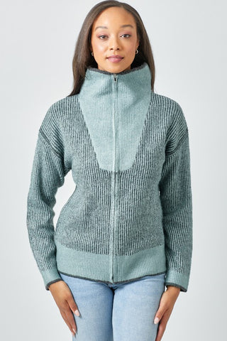 Woman wearing a green zip-up sweater against a plain background