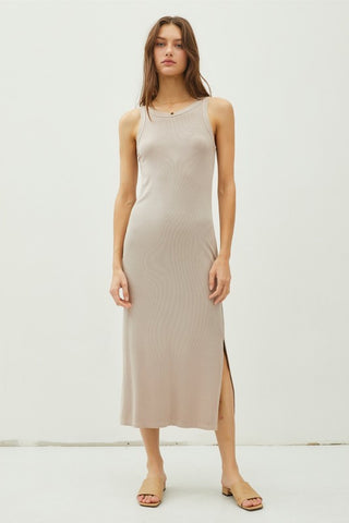 Woman wearing a beige sleeveless dress with a slit on a white background