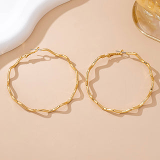 Gold hoop earrings on a beige surface with a soft focus background