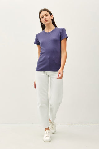 Woman wearing an indigo t-shirt and white pants on a white background