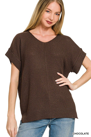 A woman modeling a brown short-sleeve knit top with a wide scoop neckline and rolled cuffs, paired with blue jeans against a plain white background.