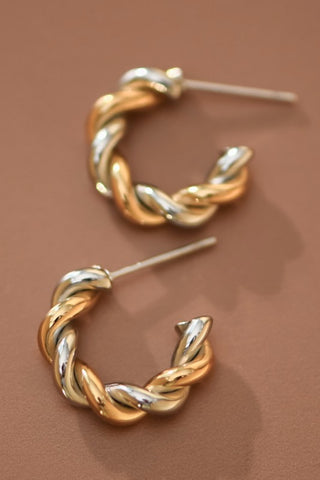 Pair of gold and silver hoop earrings on a brown background