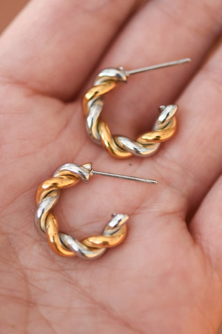 Gold and silver hoop earrings held in a hand.