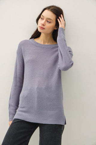Woman wearing a dusty slate sweater against a plain background