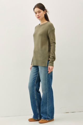 Person wearing a green sweater and blue jeans on a white background