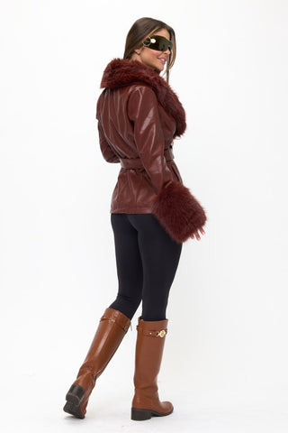 Person wearing a brown leather jacket with fur trim and brown boots on a white background