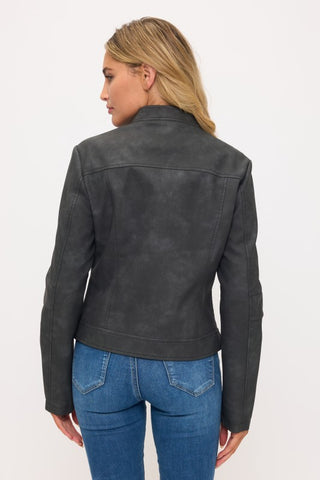 A woman shown from the back wearing a dark charcoal gray faux-leather jacket and blue jeans, photographed against a plain white studio background.