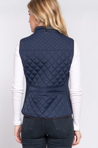Person wearing a navy quilted vest on a white background
