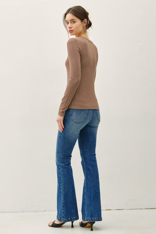 Woman wearing a brown sweater and blue jeans on a white background