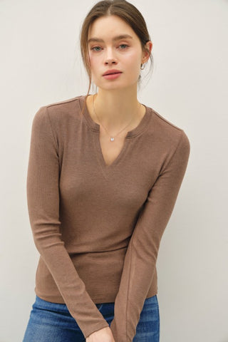 Woman wearing a brown long-sleeve top against a plain background