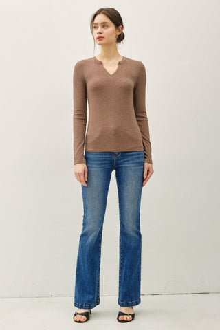 Woman wearing a brown sweater and blue jeans against a white background