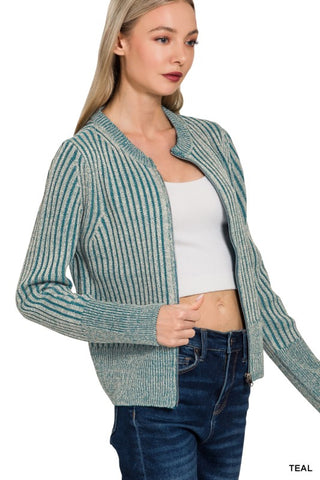 A woman wearing a teal and white vertically striped knit cardigan over a white crop top and dark blue jeans, shown against a plain white background with the word 'TEAL' in the bottom right corner.