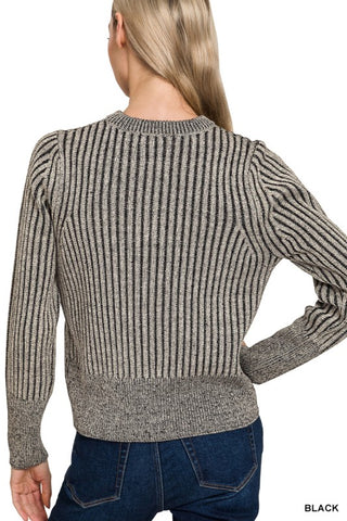 A woman shown from the back wearing a ribbed knit sweater in a heathered black and gray color, paired with blue jeans against a plain white background.