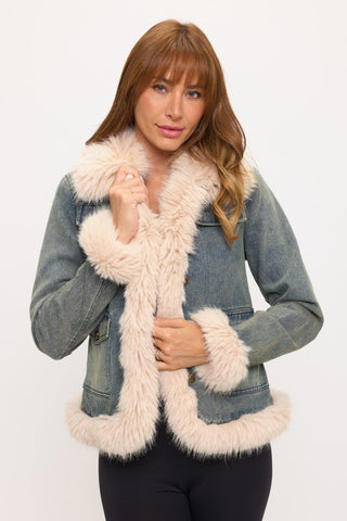 Woman wearing a denim jacket with pink fur trim on a white background