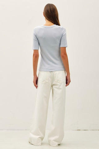 Person wearing a light gray t-shirt and white pants on a plain background