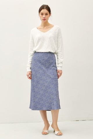 Woman wearing a white blouse and blue patterned skirt on a white background