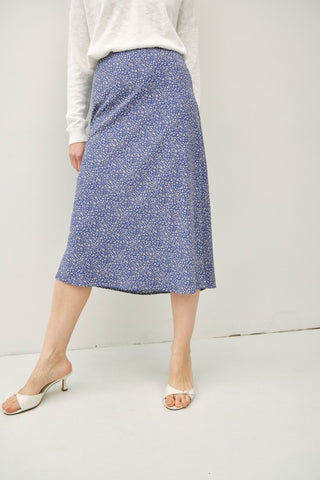Person wearing a blue floral skirt on a white background