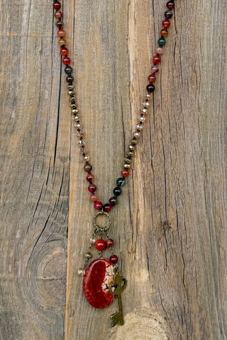 Beaded necklace with a red pendant on a wooden surface