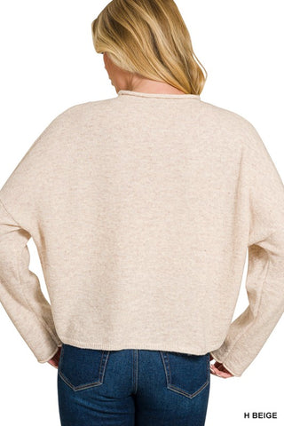 Person wearing a beige sweater and blue jeans on a white background