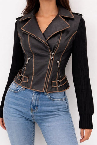 Person wearing a black leather vest with brown stitching, black long-sleeve top, and blue jeans on a white background