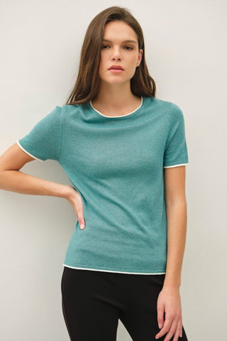 Woman wearing a teal t-shirt with white trim against a plain background