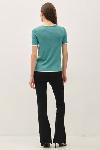 Woman wearing a teal top and black pants on a white background
