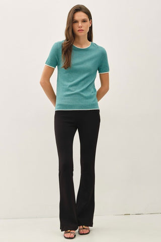 Woman wearing a teal shirt and black pants on a white background