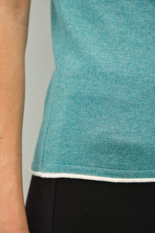 Close-up of a teal shirt with a white trim on a plain background