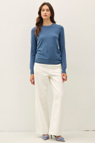 Woman wearing a blue long sleeved shirt, white pants and heels.