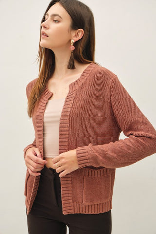 Woman wearing a brown knitted cardigan against a plain background