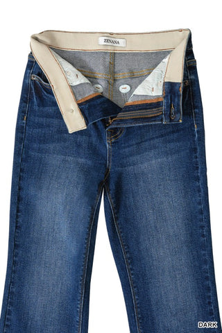 A pair of dark blue denim jeans shown from the back, featuring a large beige button closure at the waistband and a visible inner label reading 'ZENANA'.