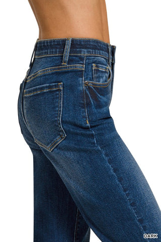 Close-up side view of a person wearing dark blue denim jeans, showing the back pocket and waistband against a plain white background.