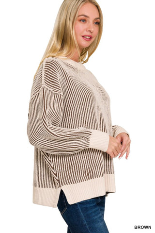 A woman wearing a brown and cream striped knit sweater with blue jeans, shown from a side profile against a plain white background.