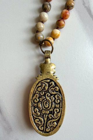 Necklace with a detailed pendant and beaded chain on a white background