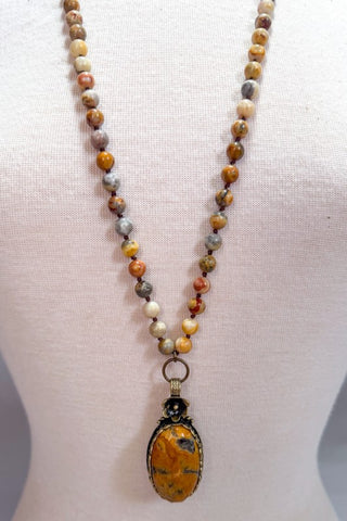 Beaded necklace with a pendant on a mannequin bust against a white background