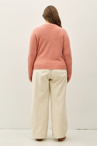 Back of a woman wearing a pink sweater and white pants