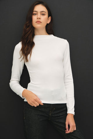 Woman wearing a white long sleeved top against a black background